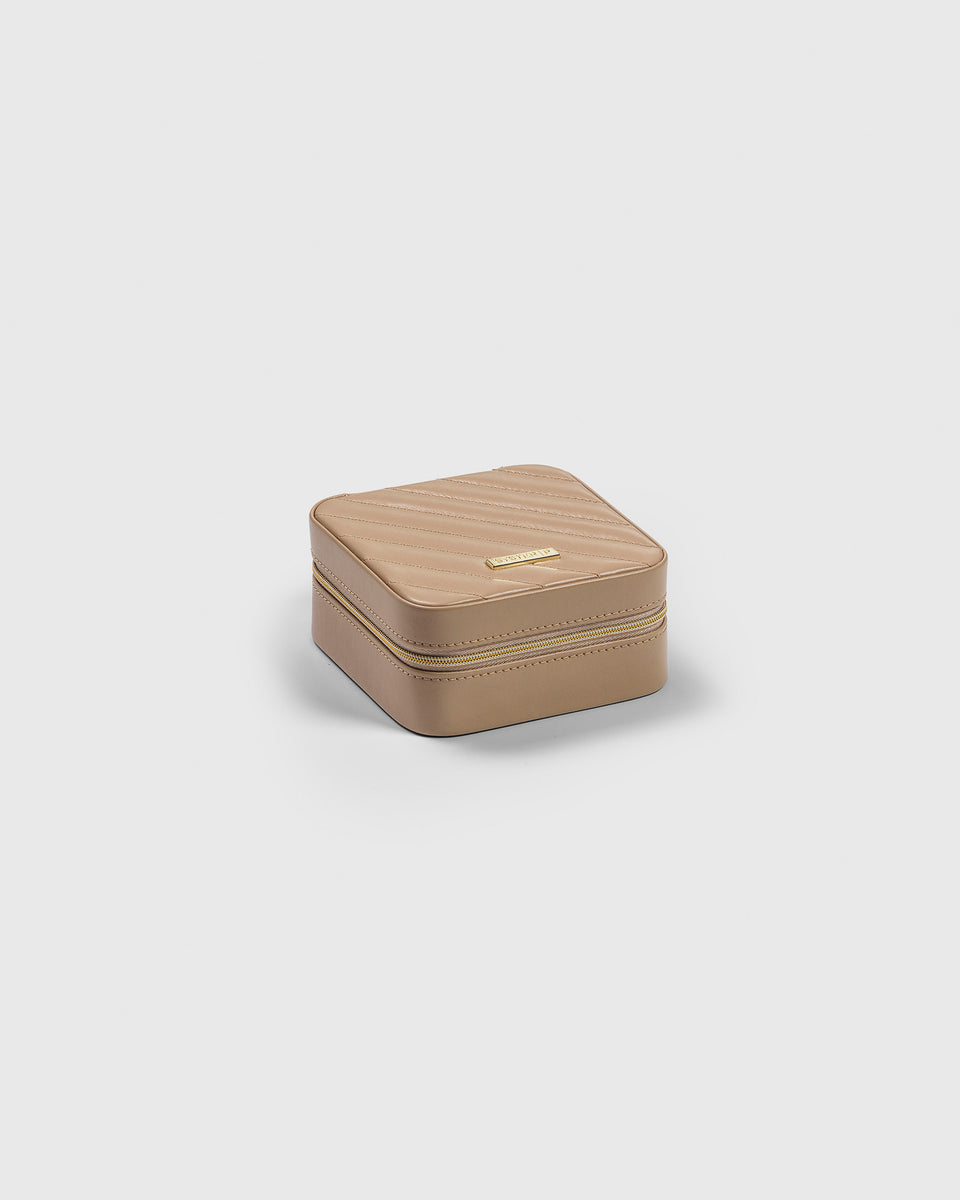 A product shot of the Jewelry Case Small in beige, featuring a quilted vegan leather top, a gold zipper, and the Syster P logo.
