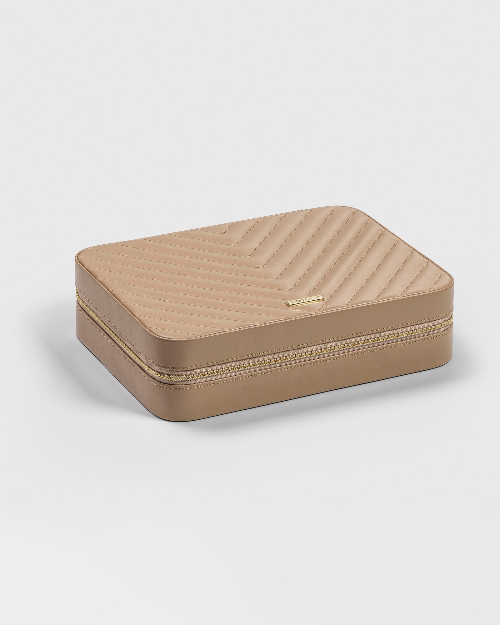 A product shot of the Syster P large jewelry case in beige, featuring a stitched chevron pattern on the lid and a gold-colored zipper.