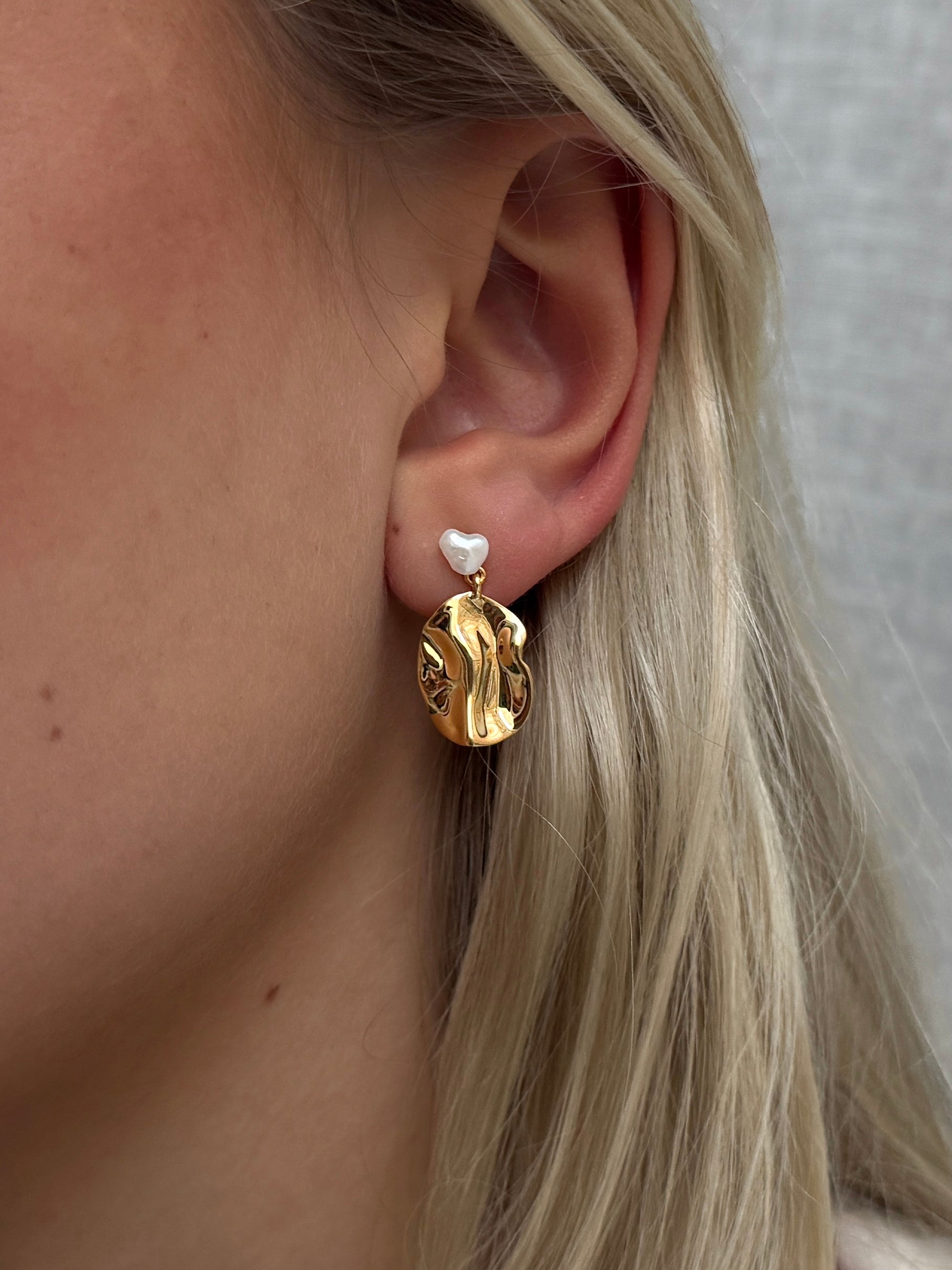 Golden earring shaped like a leaf with a small freshwater pearl