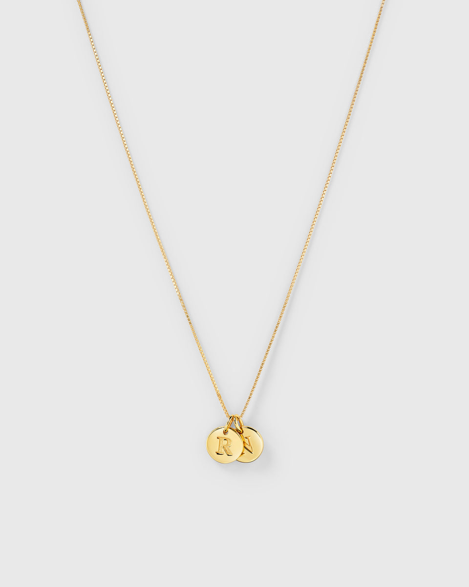 A product shot of the Beloved Medium Box Chain in gold, styled with two Beloved Mini Letter charms featuring the initials 'R' and 'N'.