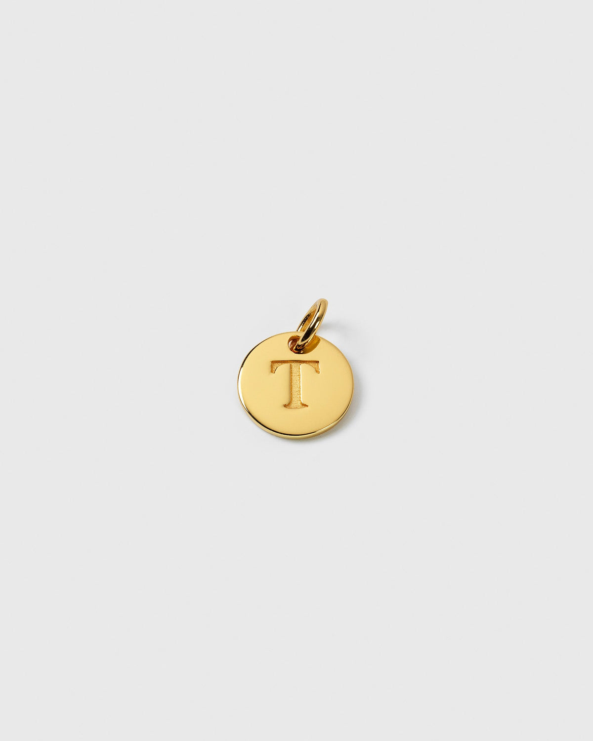 A product shot of the Beloved Mini Letter Gold charm, featuring a small round disc with the engraved letter 'T'.