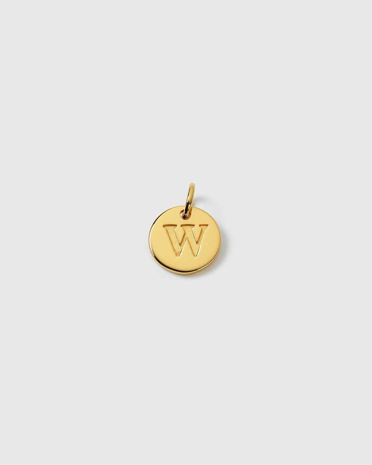 A product shot of the Beloved Mini Letter Gold pendant, a small circular charm with the letter 'W' engraved in the center.