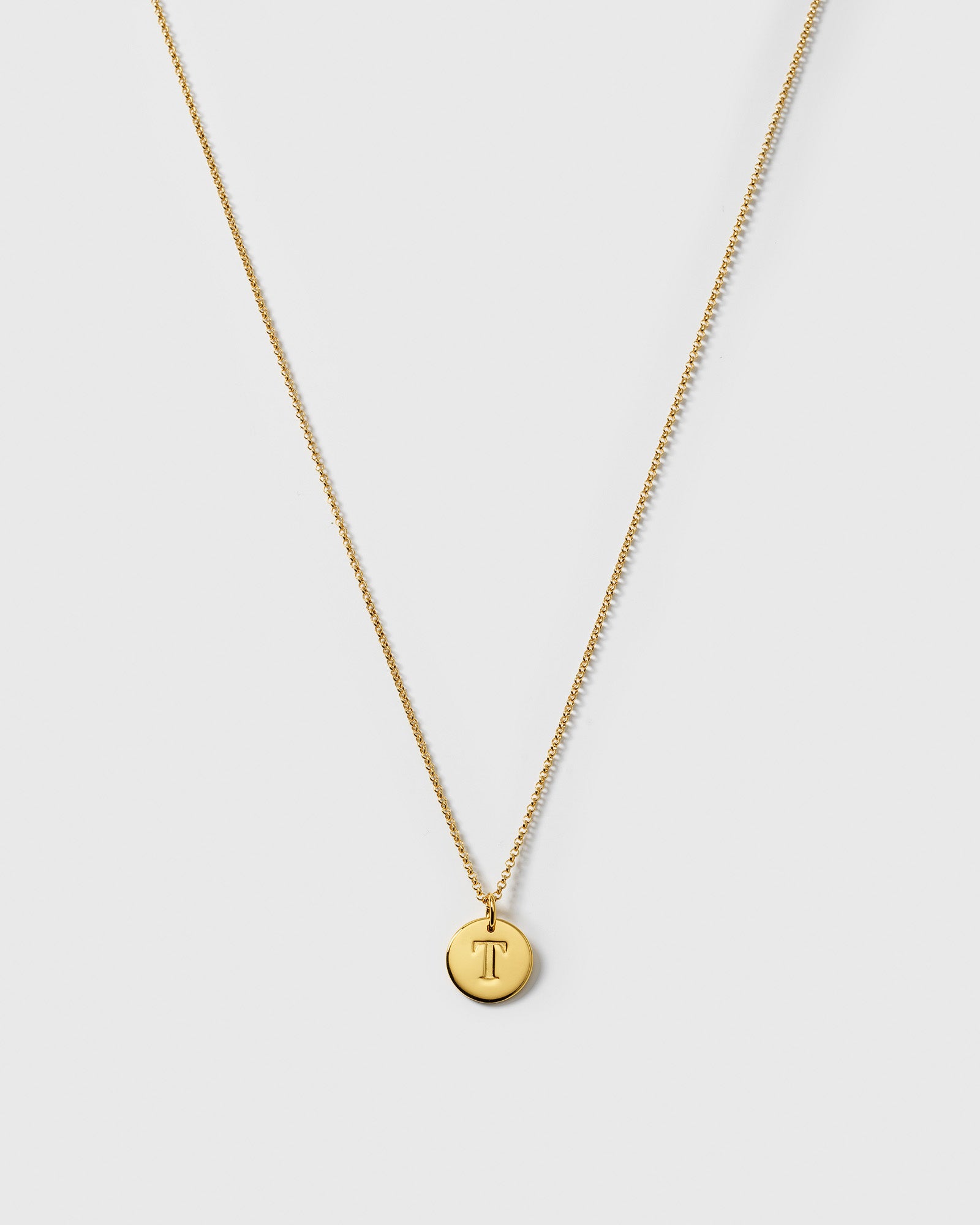 A product shot of the Beloved Medium Rolo Chain in gold, shown with a round gold pendant engraved with the letter 'T'.