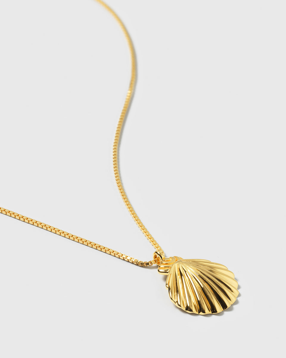 A close-up of the gold Beaches Shell Necklace, featuring a detailed, ridged shell-shaped pendant on a fine box chain.