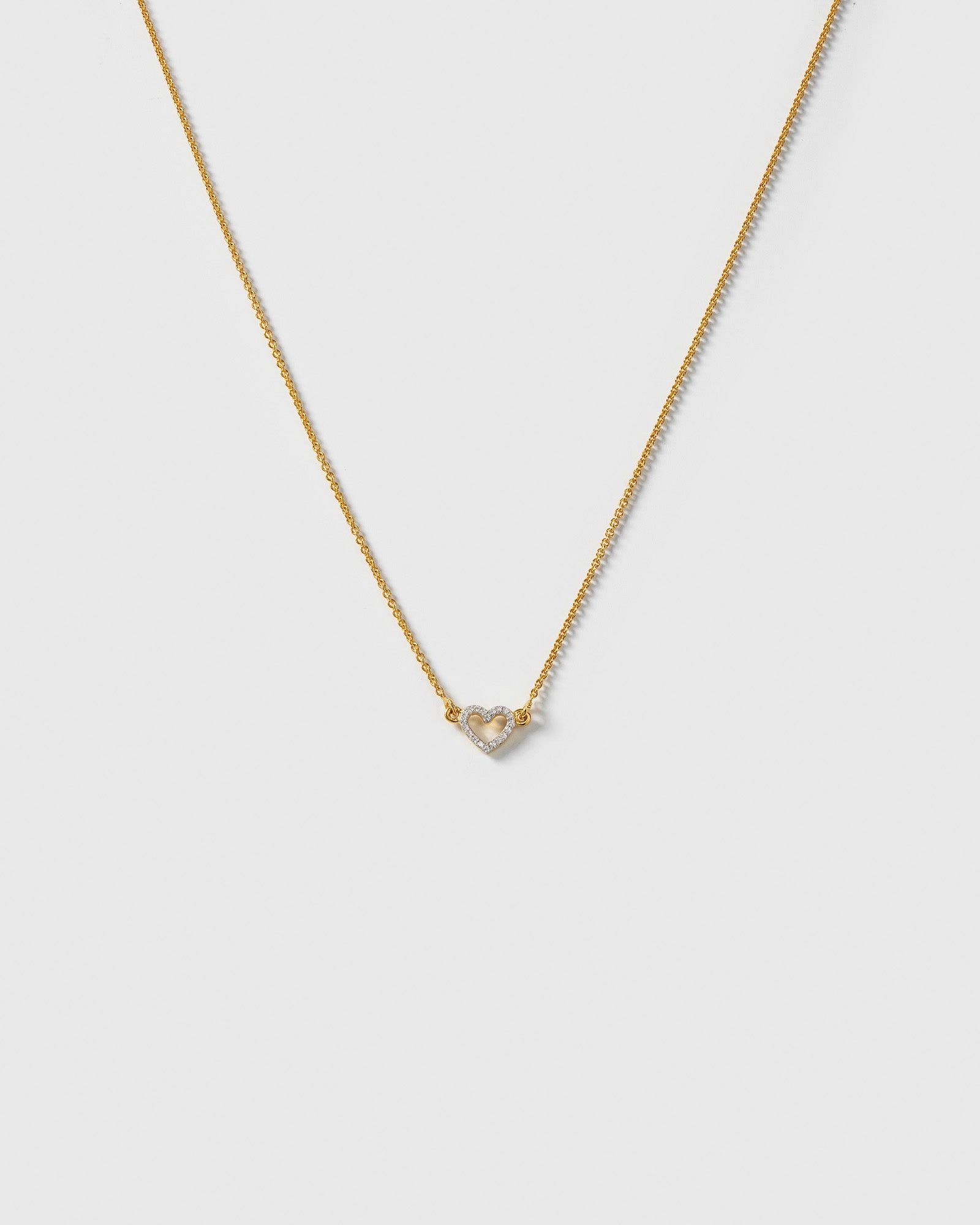 A product shot of the Snap Heart Necklace in gold, featuring a fine chain and a heart-shaped pendant covered in clear crystal stones.