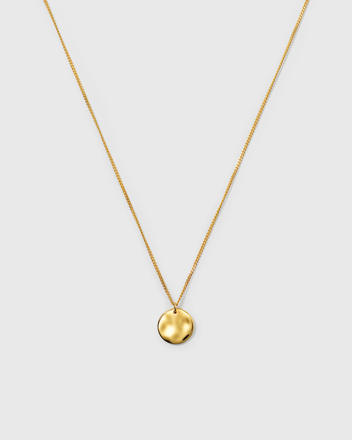 A product shot of the Minimalistica Hammered Circle Necklace in gold, showcasing its fine chain and round, hammered-finish pendant.
