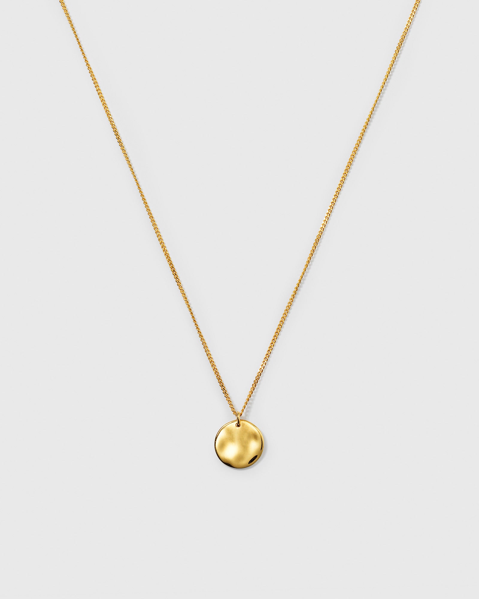 A product shot of the Minimalistica Hammered Circle Necklace in gold, showcasing its fine chain and round, hammered-finish pendant.
