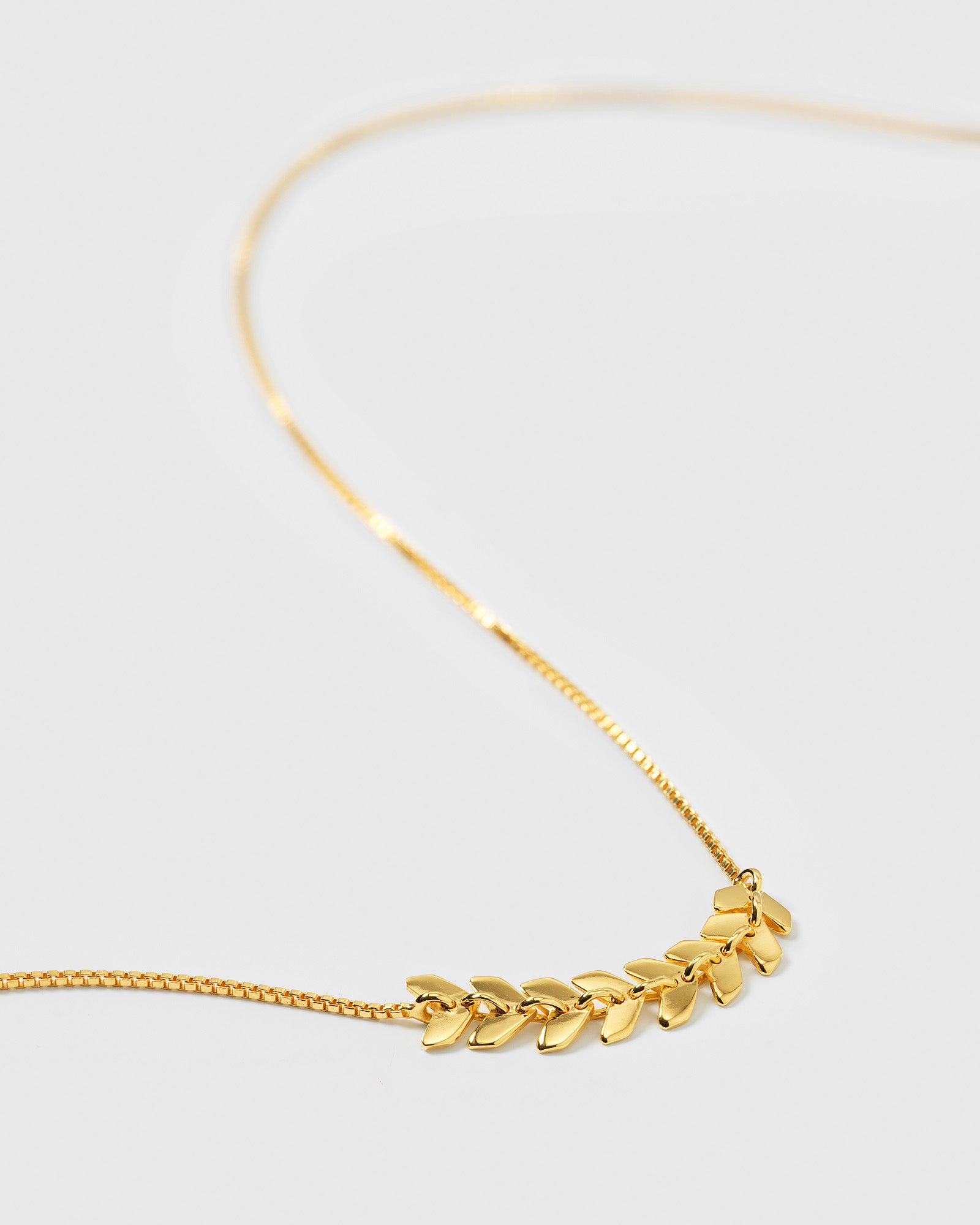 A product shot of the Layers Simone Necklace in gold, highlighting the central design of small, leaf-like charms on a fine box chain.
