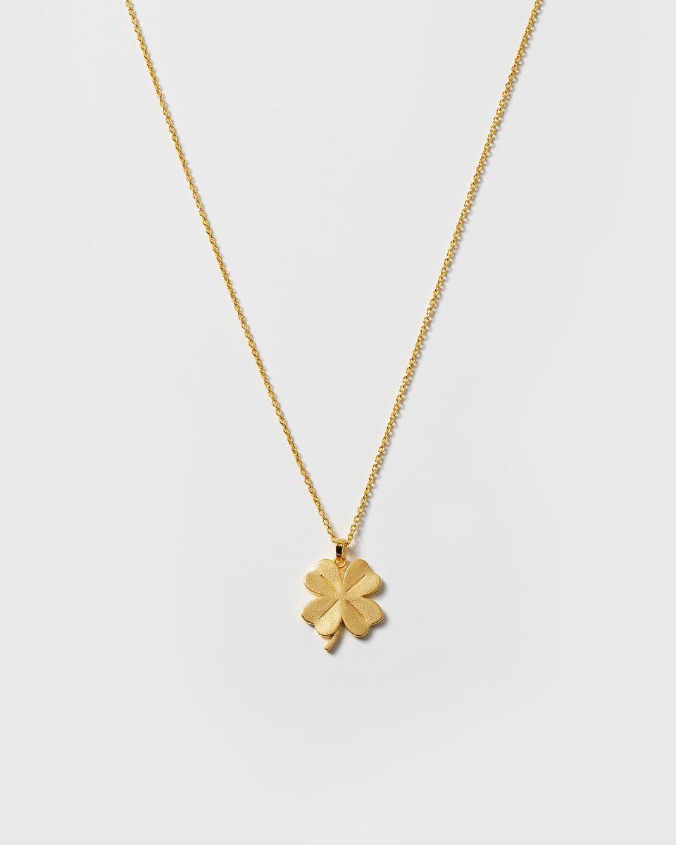 A product shot of the Beaches Fortune Necklace in gold, featuring a fine oval chain and a matte four-leaf clover pendant.