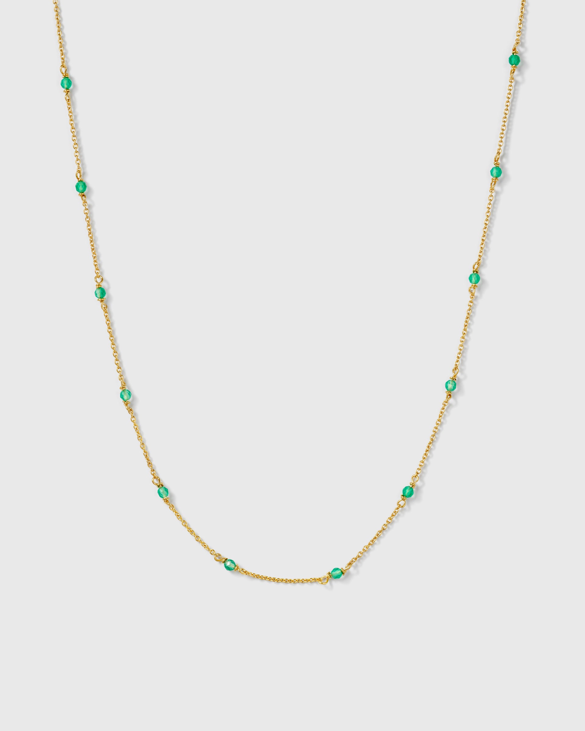 A product shot of the Santa Monica Necklace in gold, featuring a fine chain adorned with small, vibrant green onyx stones spaced evenly along its length.
