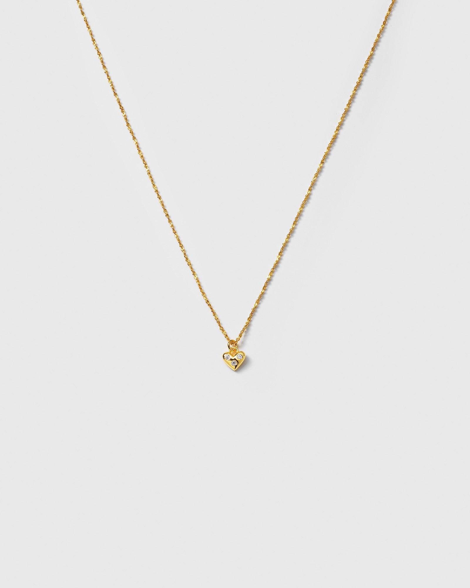 A product shot of the Forever Necklace in gold, featuring a unique twisted chain and a delicate heart pendant adorned with sparkling cubic zirconia stones.