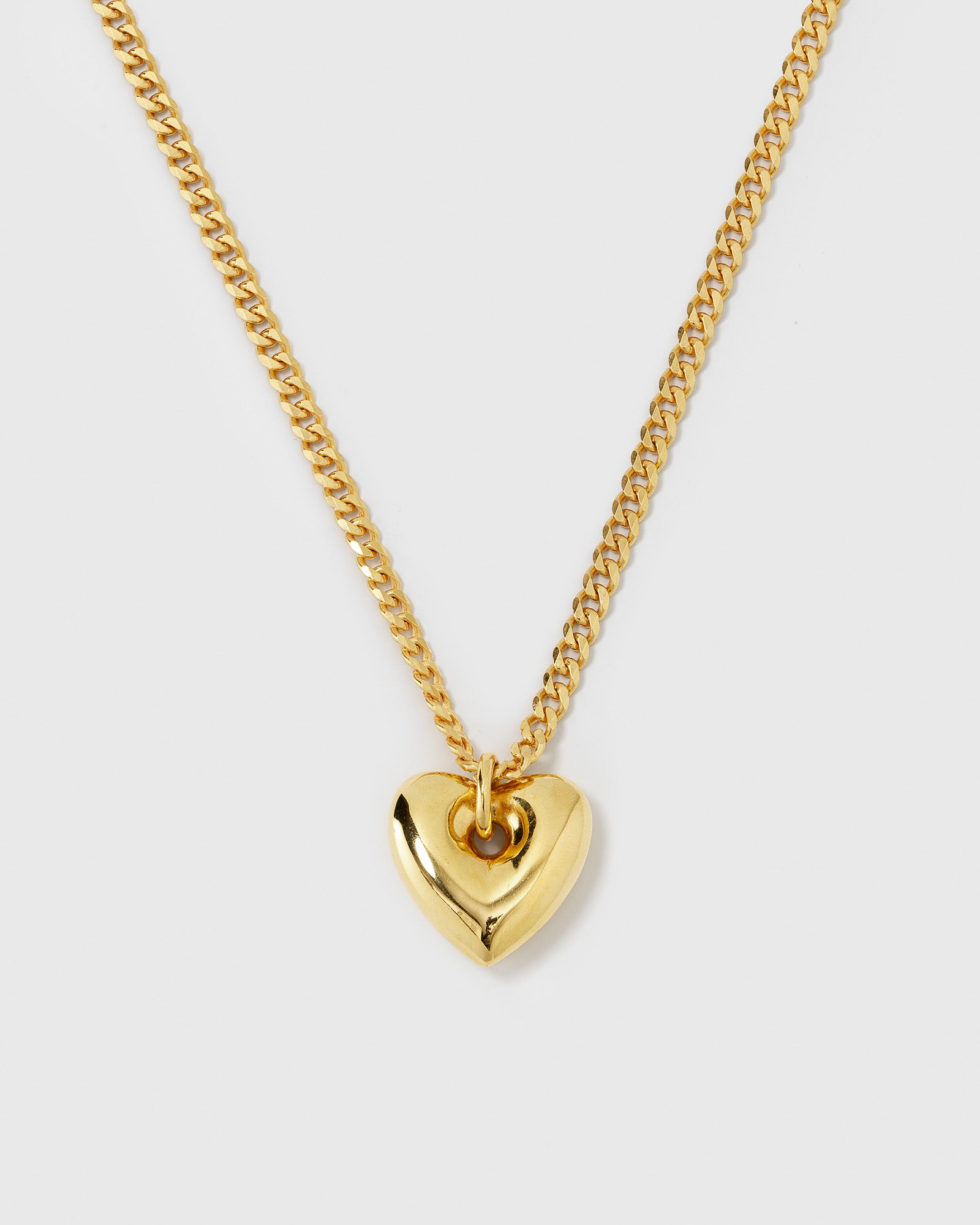 A product shot of the Fat Heart Necklace in gold, featuring a chunky curb chain and a large, puffy heart-shaped pendant.