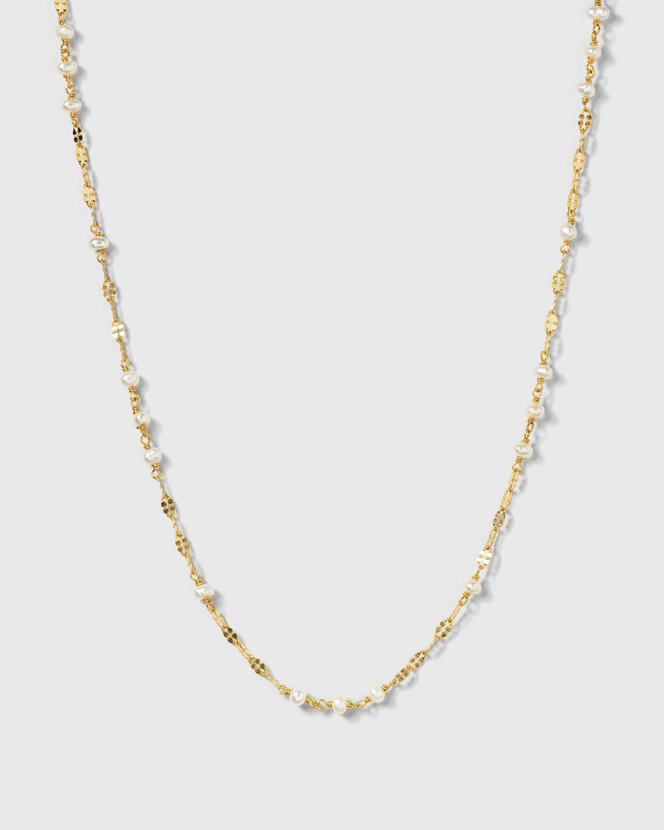 A product shot of the Aurelia Necklace Gold, featuring a unique patterned gold chain interspersed with small freshwater pearls.