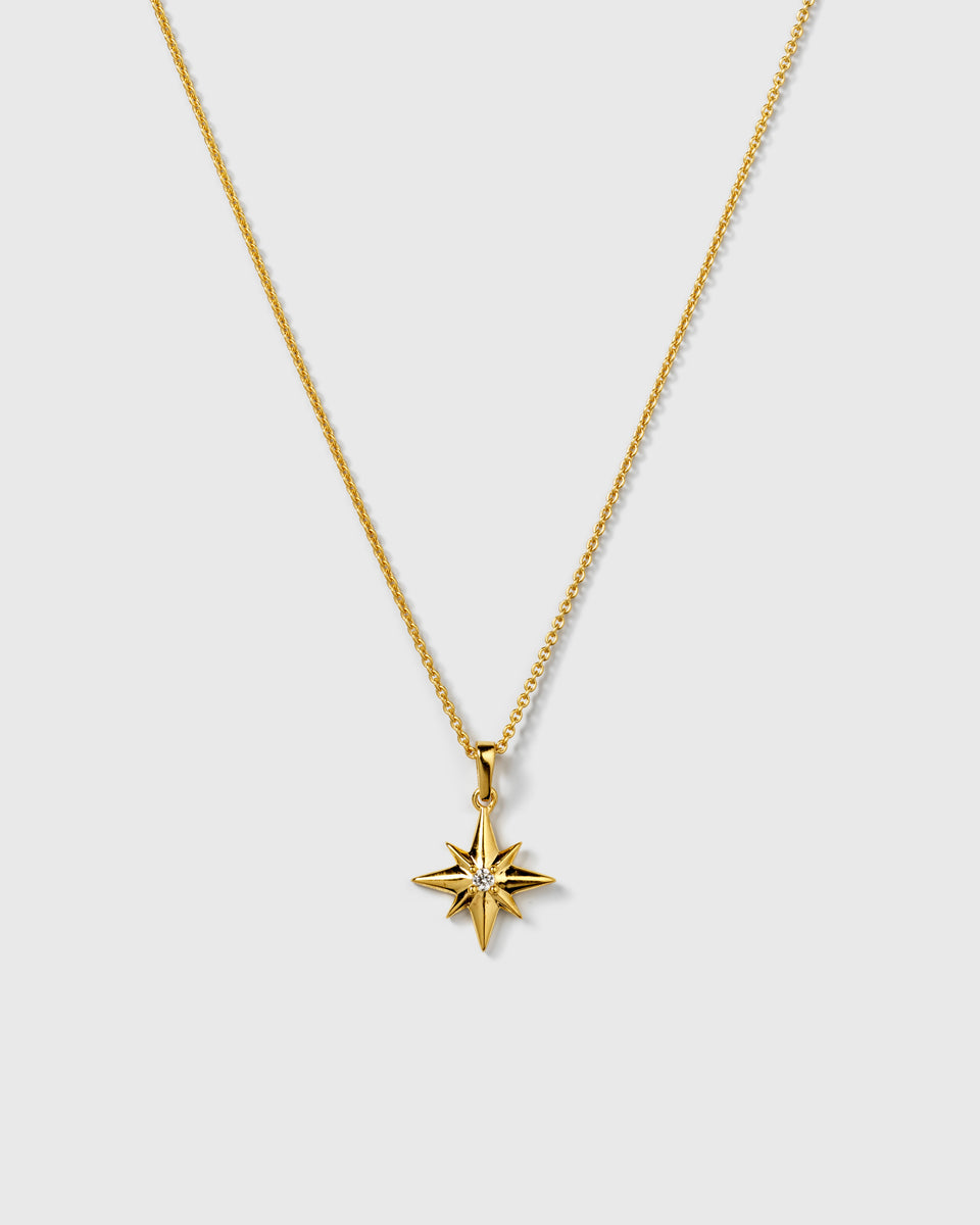 A product shot of the North Star Big Necklace in gold, featuring a fine chain and an eight-pointed star pendant with a sparkling crystal at its center.