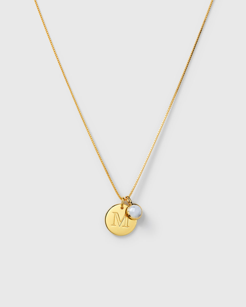 Gold necklace with two pendants: a round aquamarine March birthstone and a round letter charm.