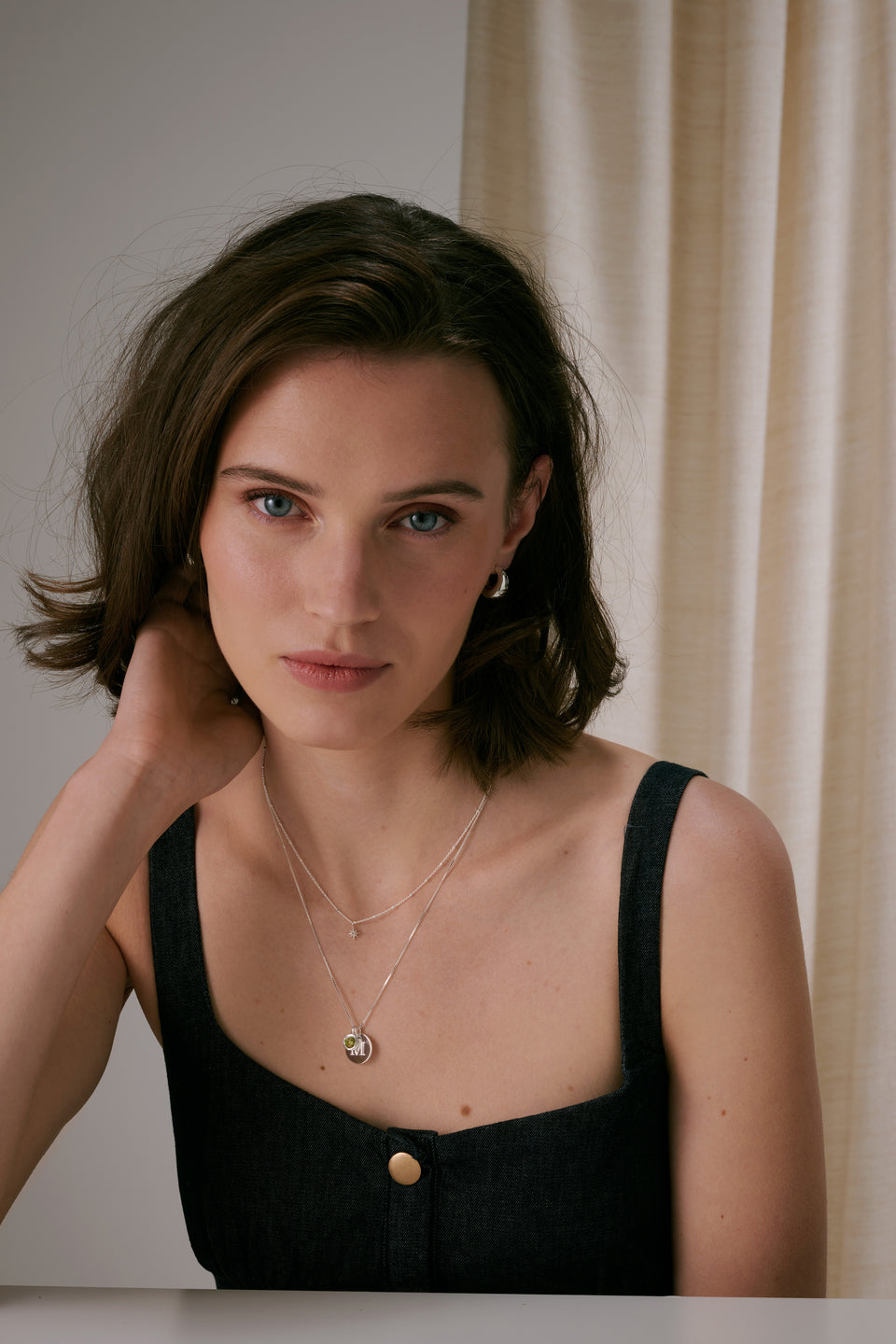 silver hoop earrings and two layered silver necklaces—one with a star charm, the other with a august birthstone and letter pendant.