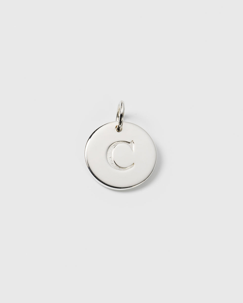 A product shot of the Beloved Big Letter silver charm, a circular pendant with the initial 'C' engraved on its surface.