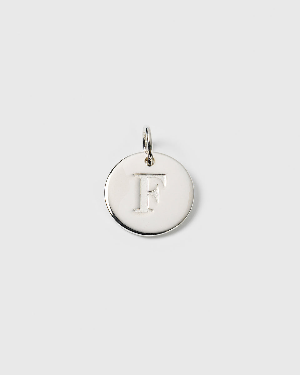 A product shot of the Beloved Big Letter Silver pendant, featuring a round charm with the letter F embossed on its surface.