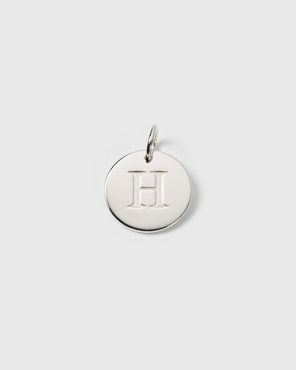 A product shot of the Beloved Big Letter Silver pendant, featuring a circular charm with the letter 'H' engraved in the center.