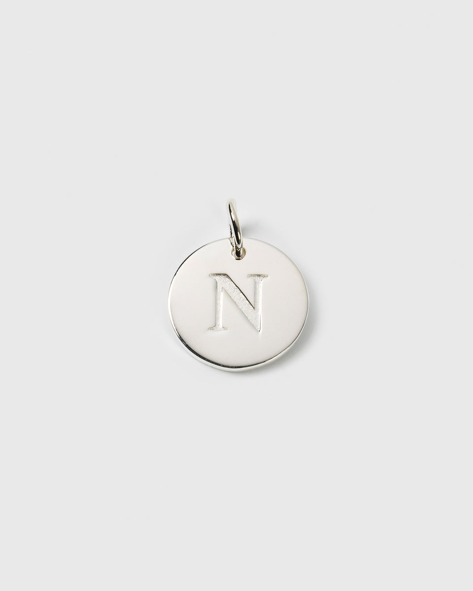 A close-up of the Beloved Big Letter Silver pendant, a circular charm with the letter 'N' engraved.