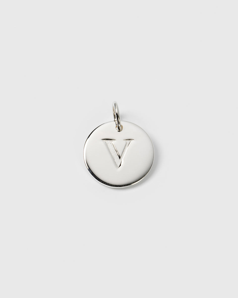 A product shot of the Syster P Beloved Big Letter pendant in silver, featuring a round charm with the letter 'V' engraved on it.