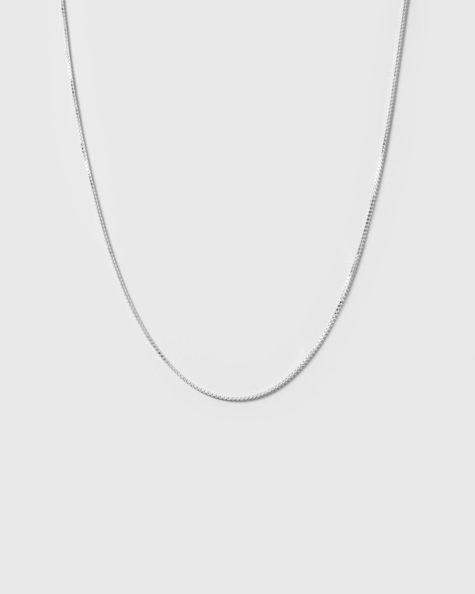 A product shot of the Beloved Short Box Chain in silver, curving gently to showcase its classic box link design.