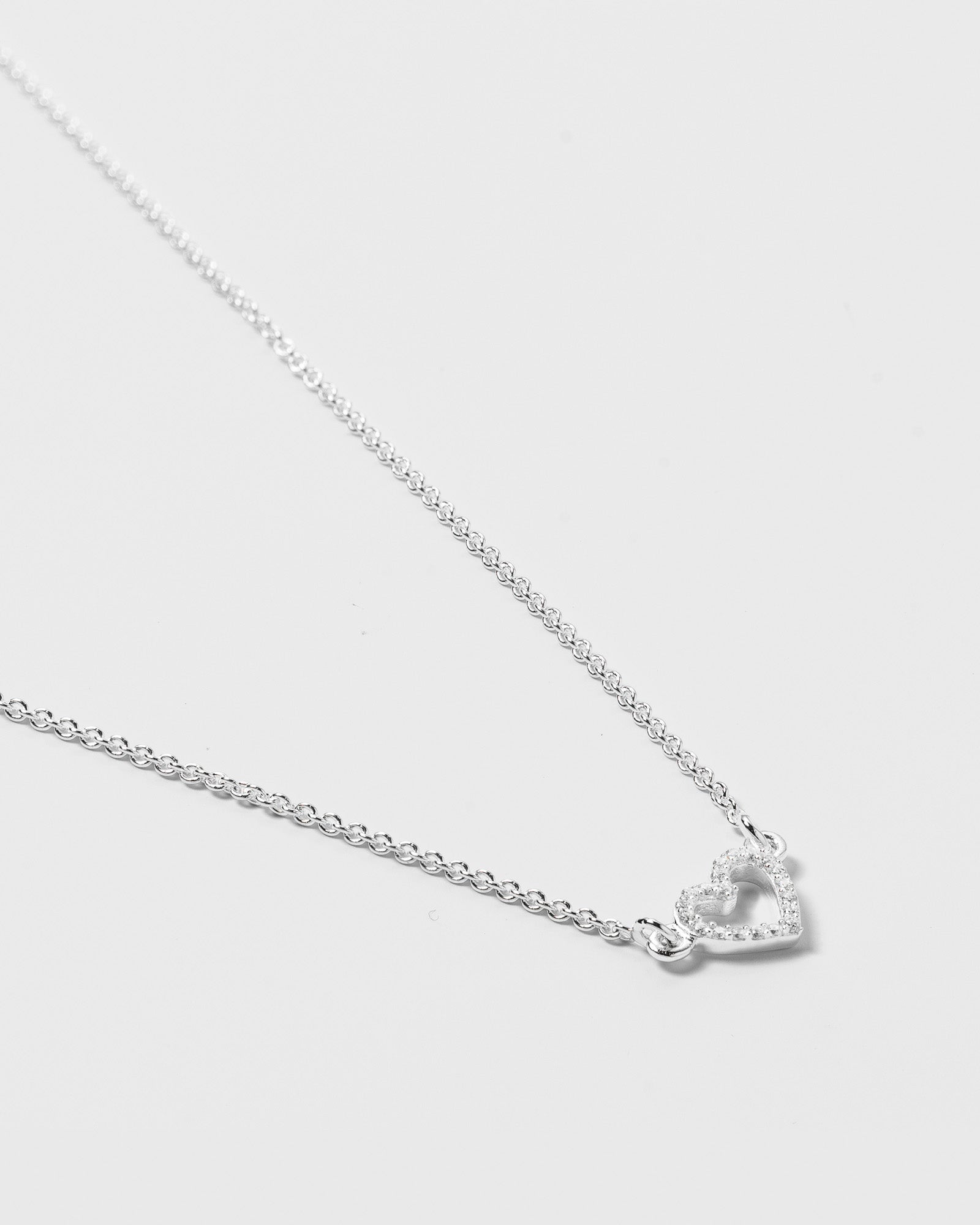 A product shot of the Snap Heart Necklace in silver, featuring a fine chain and a heart-shaped pendant covered in crystal stones.