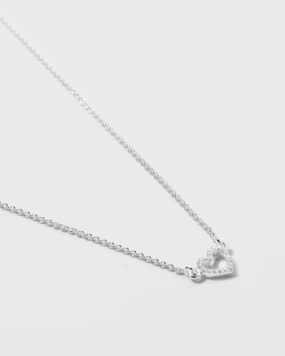 A product shot of the Snap Heart Necklace in silver, featuring a fine chain and a heart-shaped pendant covered in crystal stones.