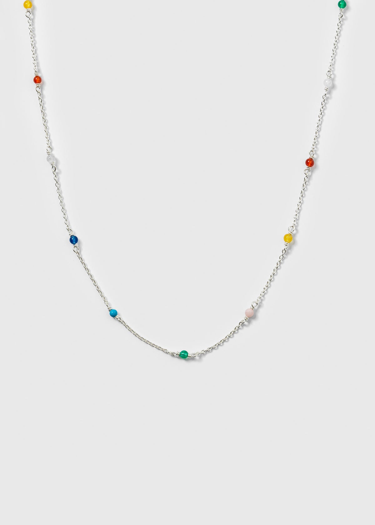 A product shot of the Santa Monica Necklace in silver, laid out to display its design of a fine chain adorned with small, colorful gemstone beads: Yellow Jade, Pink Opal, Sodalite, Green Onyx, Blue Color Reconstituted Turquoise, White Agate, and Carnelian