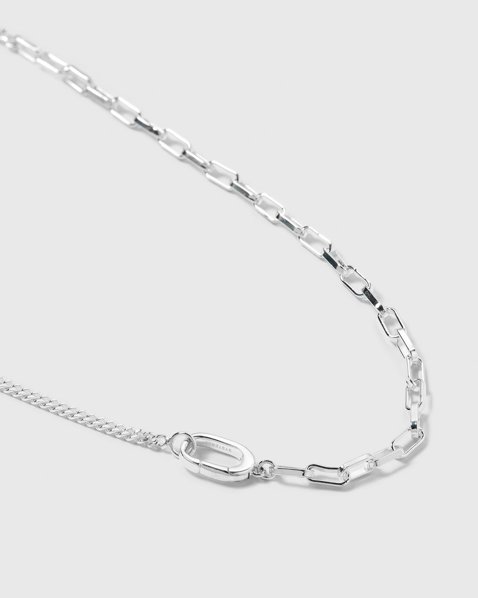 A close-up shot of the Harvey Heavy Necklace in silver, showcasing its unique design that combines two different styles of chain connected by a central, smart oval clasp.
