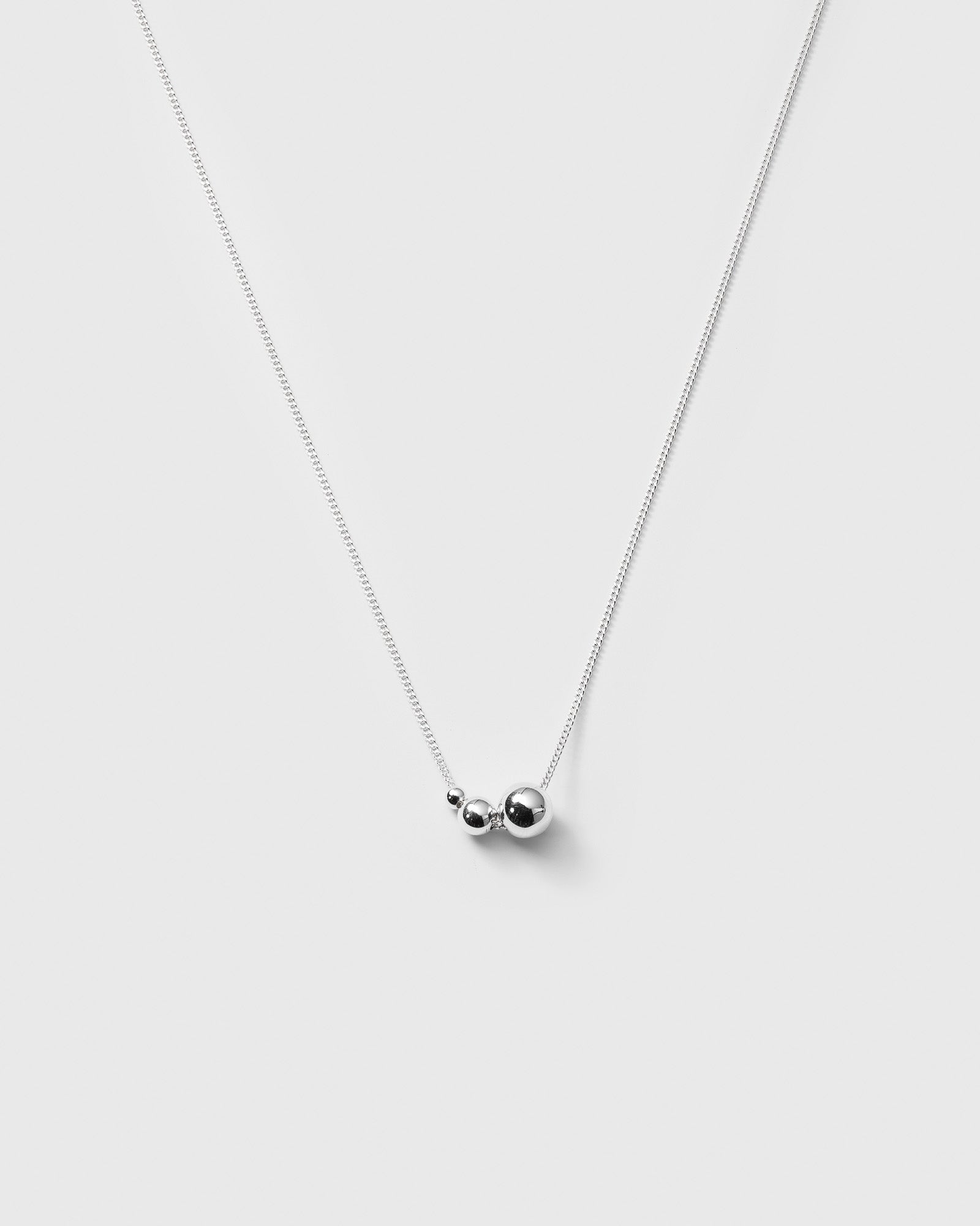 A product shot of the Universe Necklace in silver, featuring a fine chain with three polished silver balls of varying sizes.