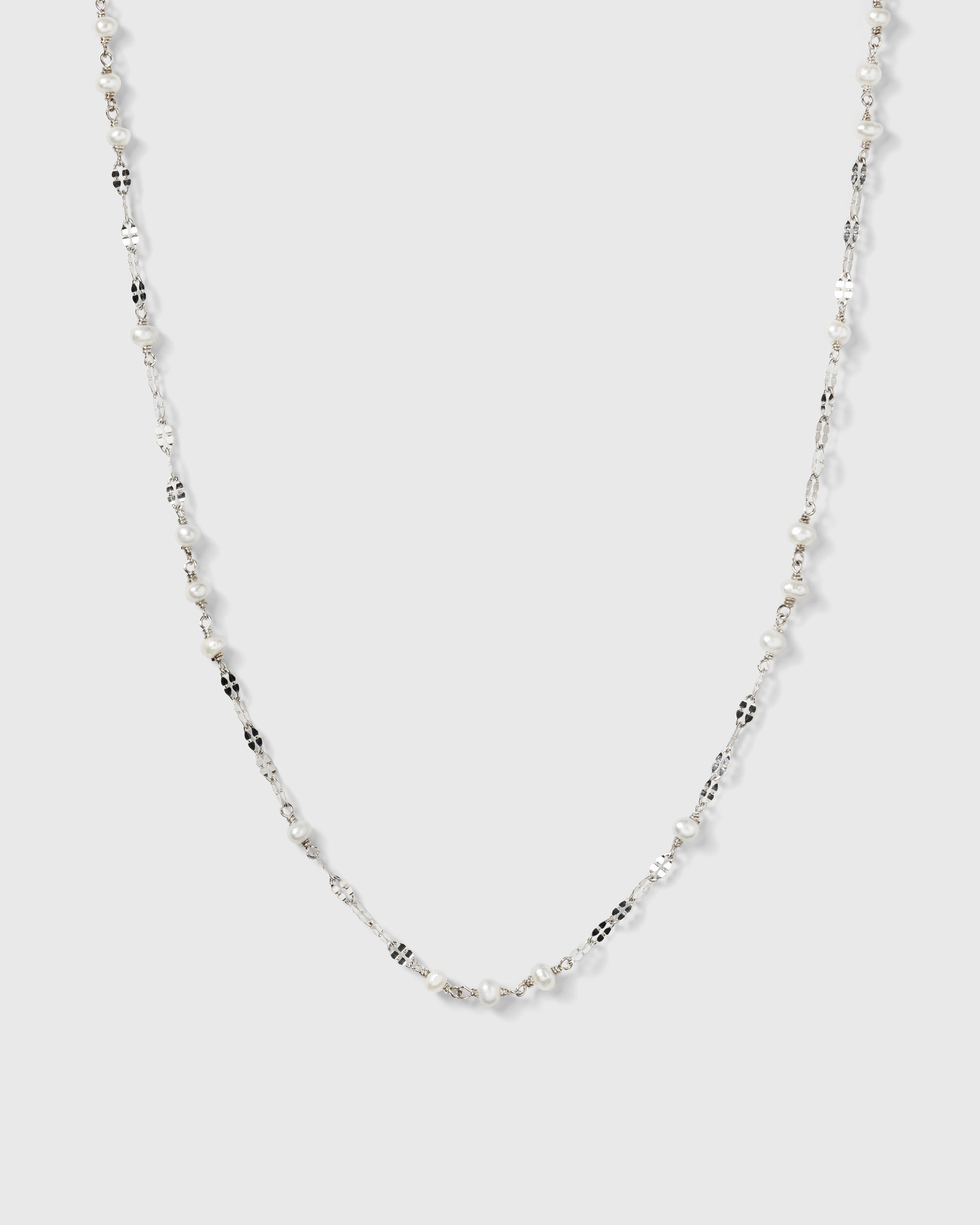 A product shot of the Aurelia Necklace in silver, laid out to showcase its unique chain design interspersed with small freshwater pearls.
