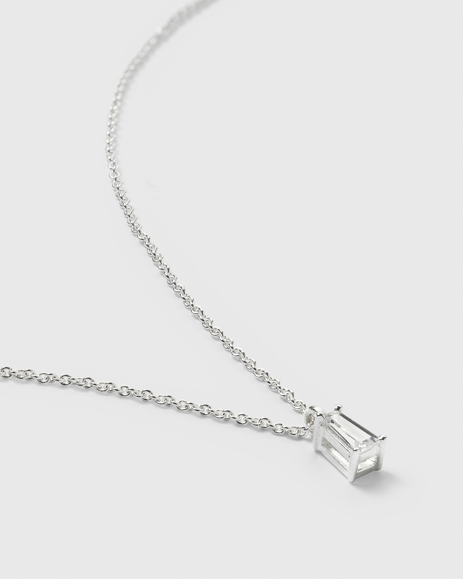 A close-up of the Iggy Necklace in silver, highlighting its delicate chain and the sparkling, tapered baguette-cut cubic zirconia pendant.