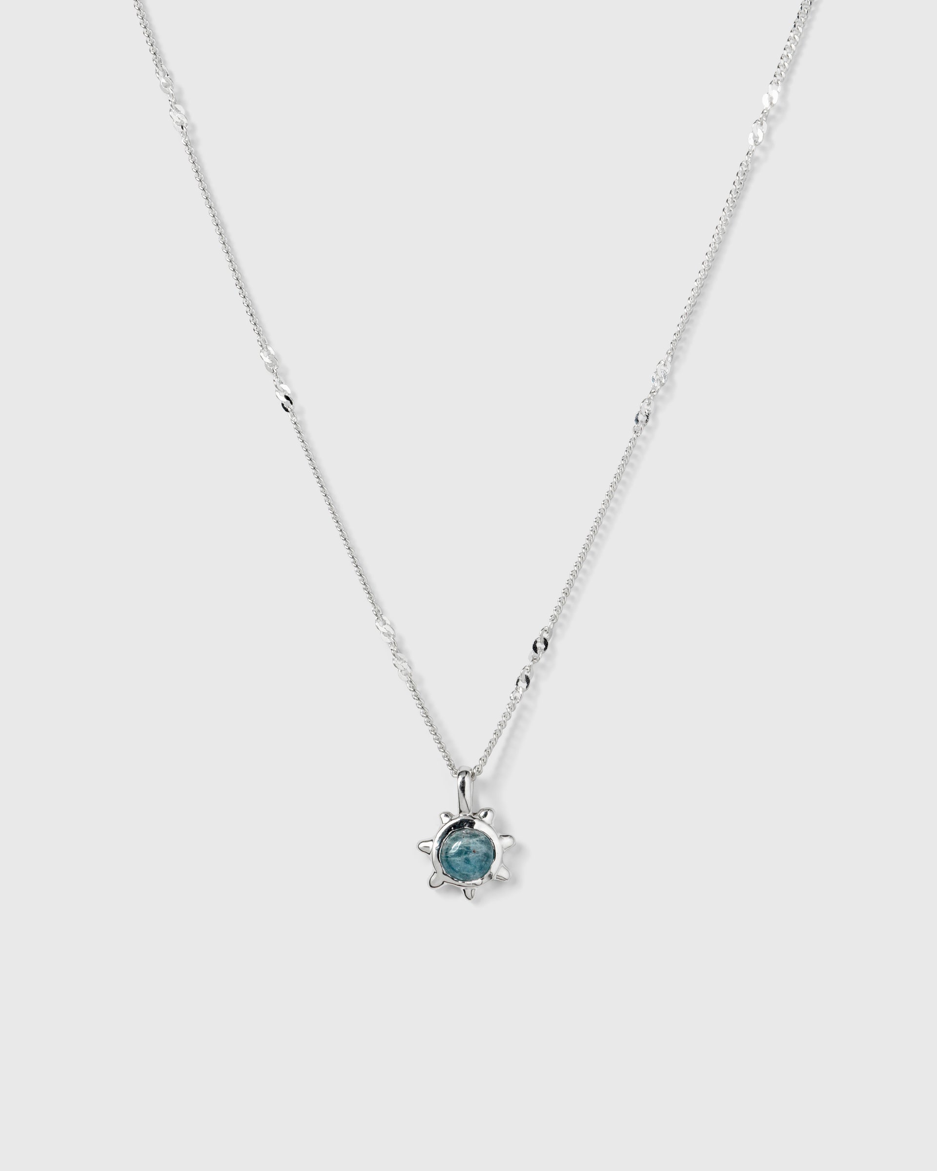 A product shot of the Florentina Necklace in silver, featuring a delicate chain with twisted links and a flower-shaped pendant with a central aquamarine stone.