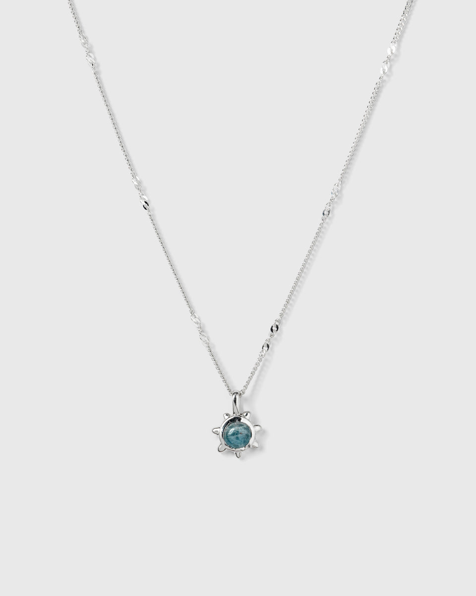 A product shot of the Florentina Necklace in silver, featuring a delicate chain with twisted links and a flower-shaped pendant with a central aquamarine stone.