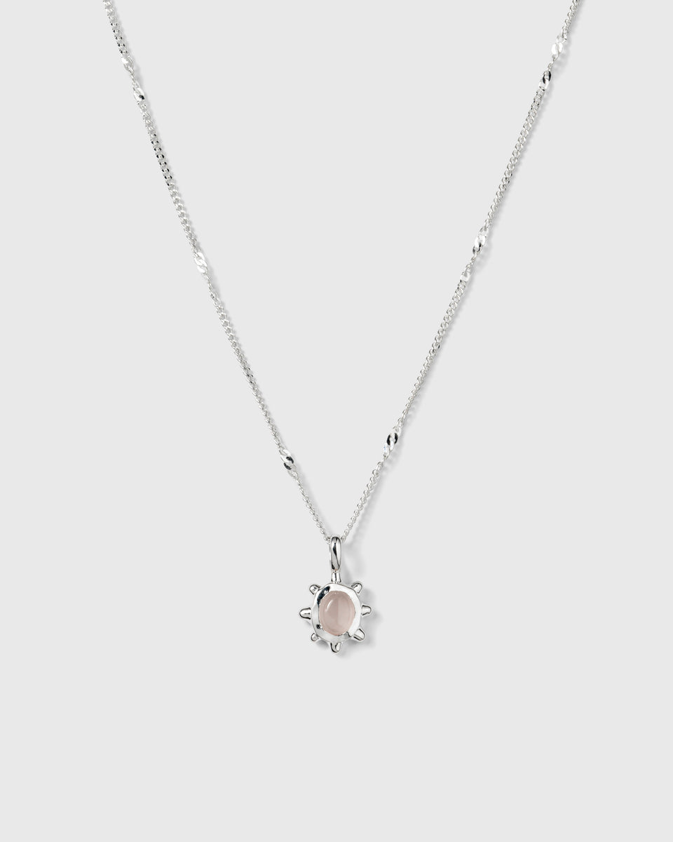 A product shot of the Florentina Necklace in silver, featuring a twisted chain and a flower-shaped pendant set with a pale pink rose quartz stone.