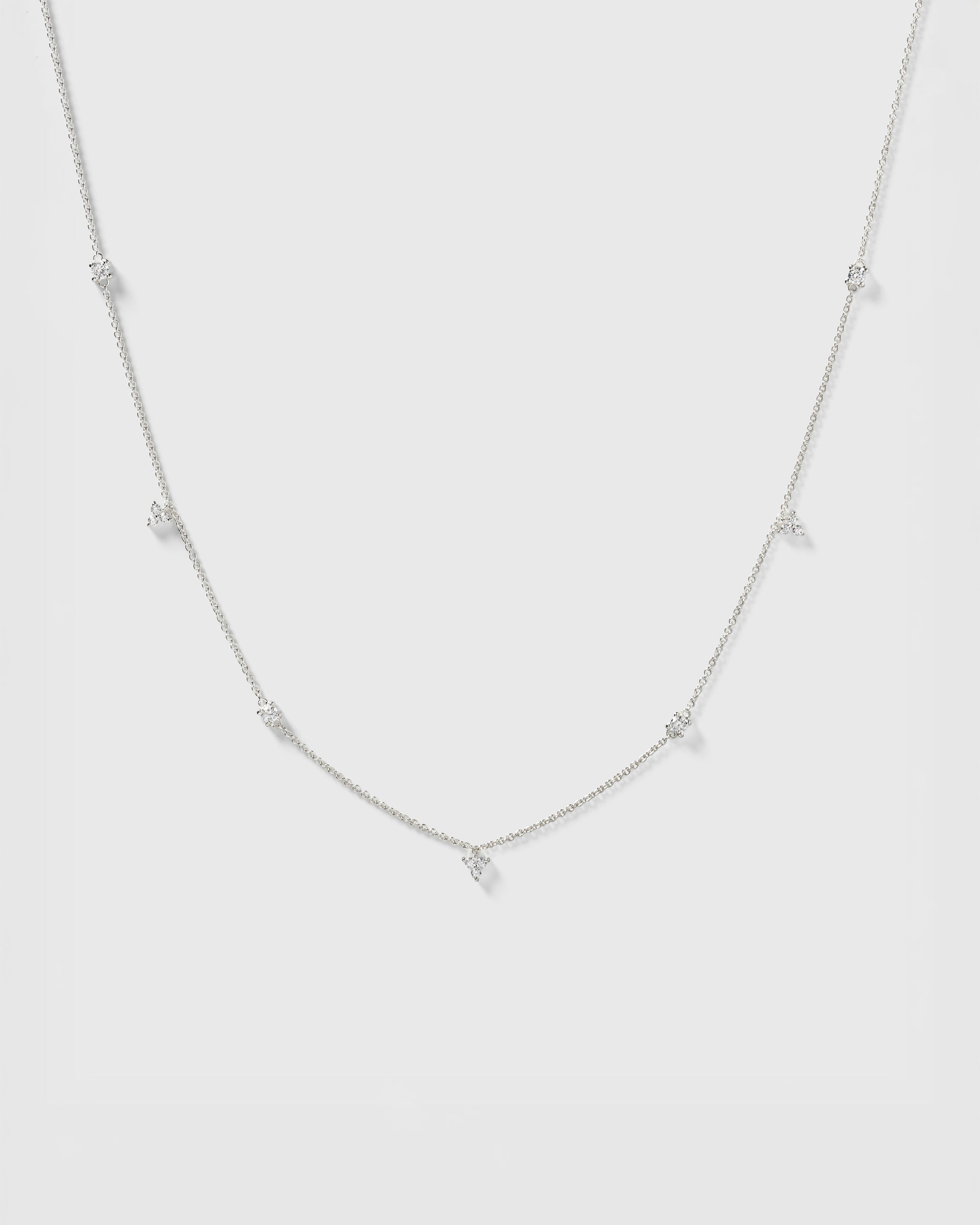 A product shot of the Celestia Necklace in silver, showcasing its fine chain adorned with several sparkling cubic zirconias in various shapes.