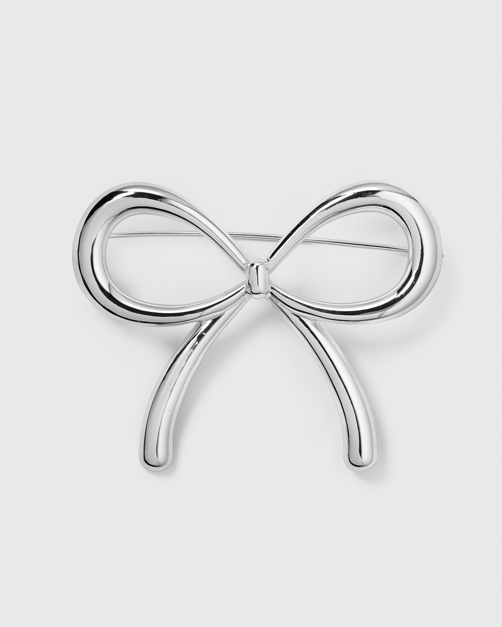 A product shot of the Ana Brooch in silver, showcasing its elegant and playful bow design.