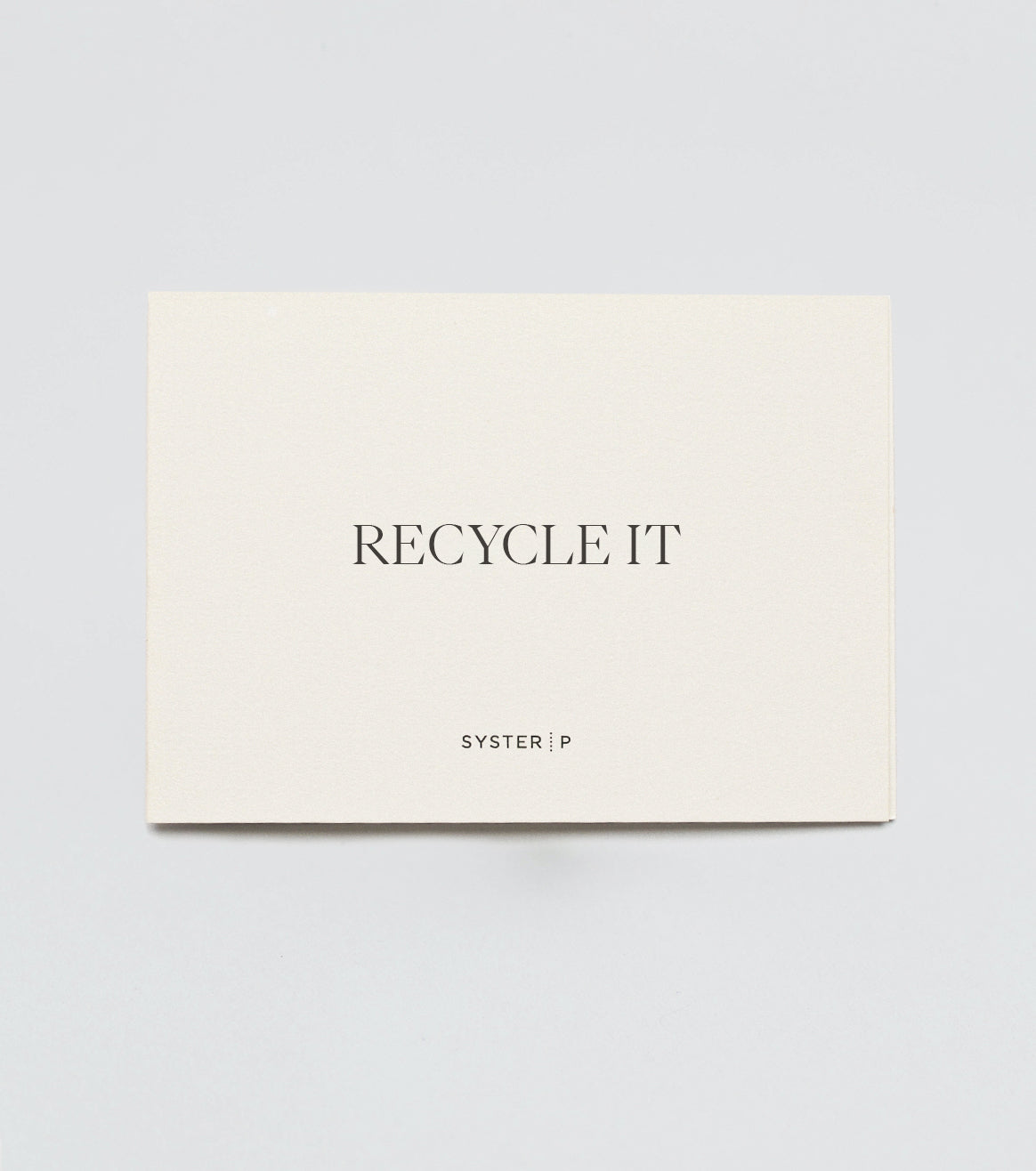 A product shot of the Syster P Recycle Coupon, showing a cream-colored card with 'RECYCLE IT' printed in the center and the brand logo below.