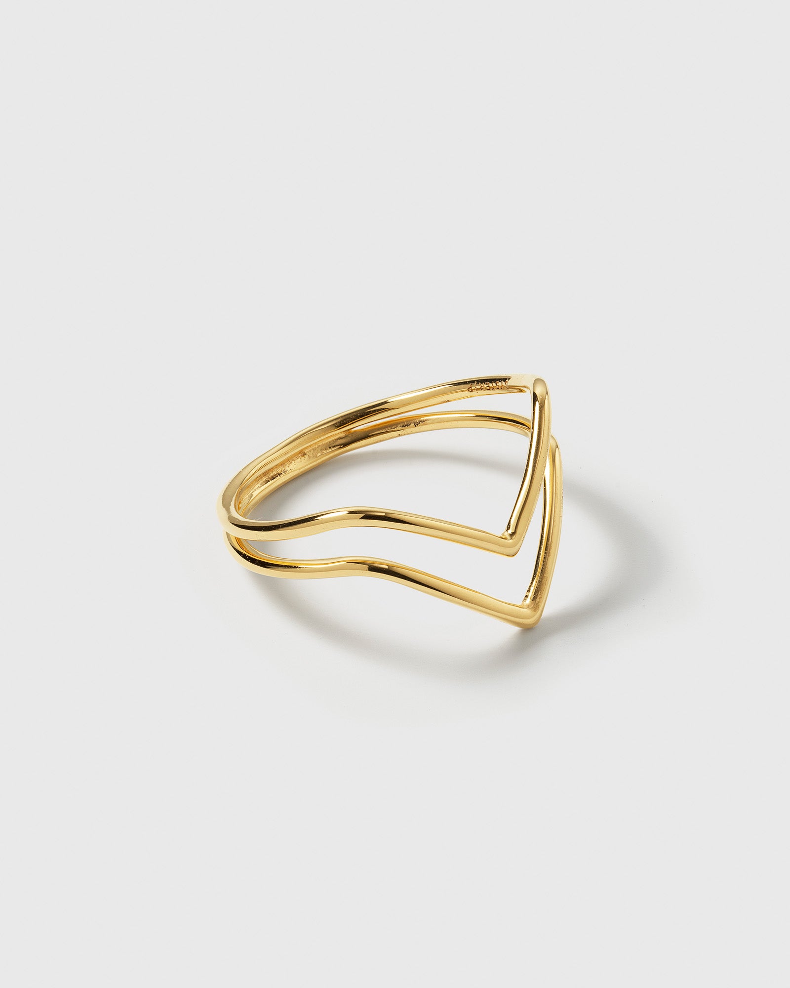 A product shot of the Tiny Arrow Ring in gold, showcasing its delicate design of two bands forming a double arrow.