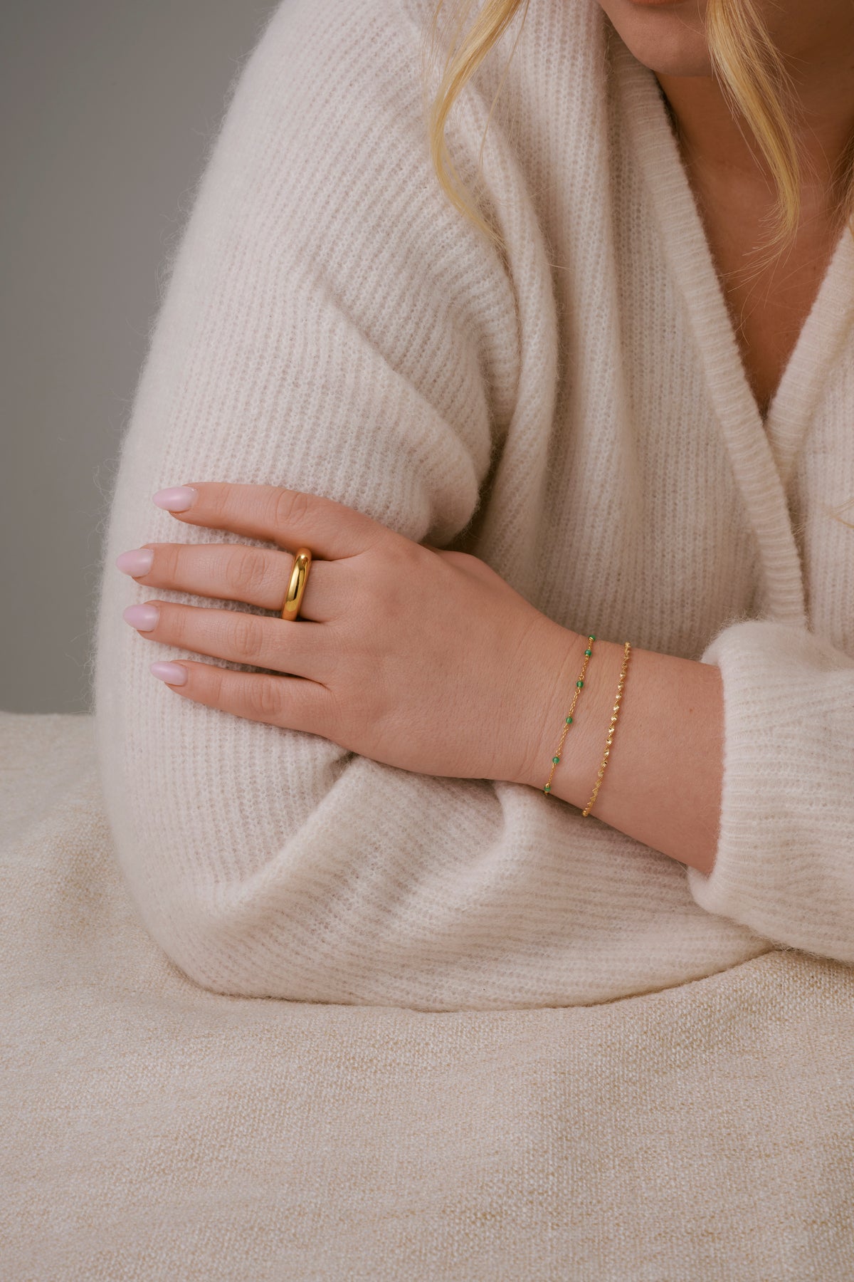A shot of a model's showcasing the Santa Monica Bracelet in gold with green onyx stones spaced throughout, layered with a twisted bracelet and paired with a chunky gold ring.