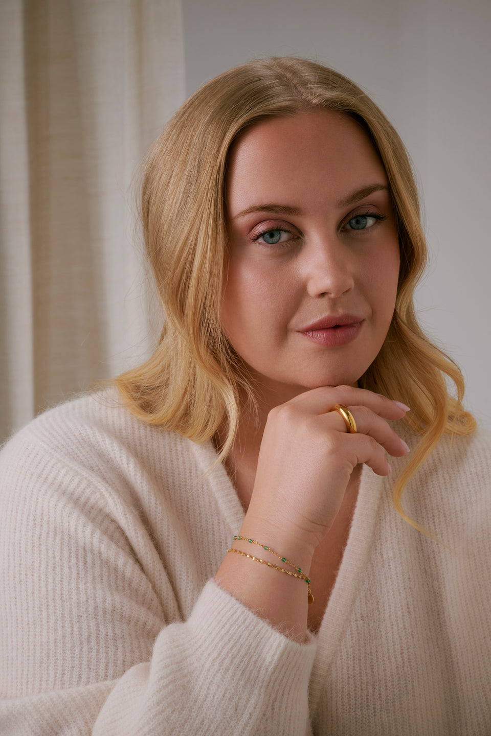 A model wearing Bolded Ring in gold, along with two delicate gold bracelets