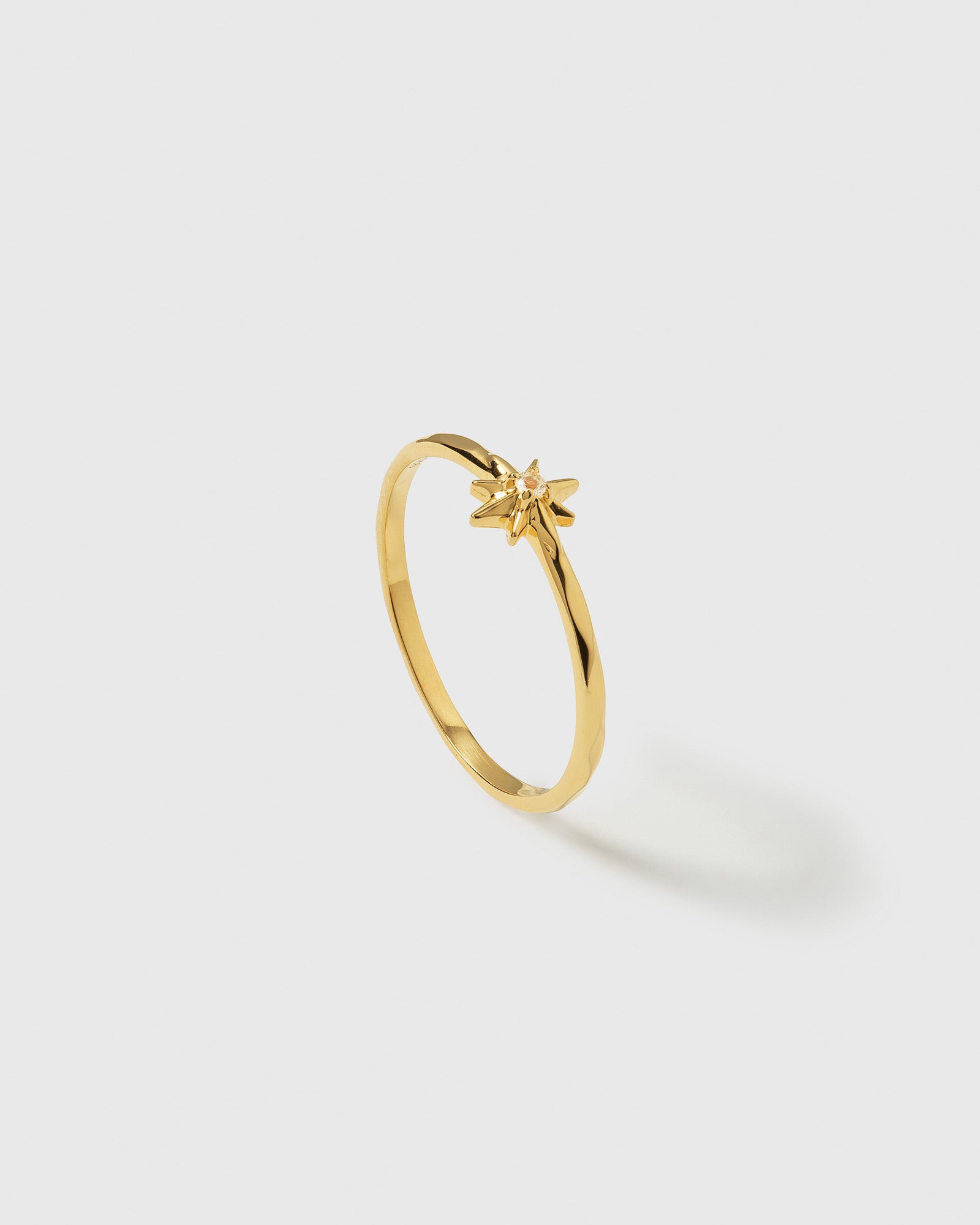 A product shot of the North Star Ring in gold, featuring a delicate, thin band with a central star motif adorned with a small crystal.