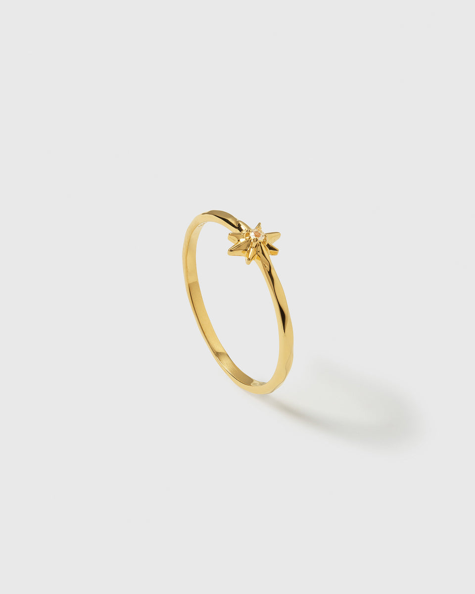 A product shot of the North Star Ring in gold, featuring a delicate, thin band with a central star motif adorned with a small crystal.