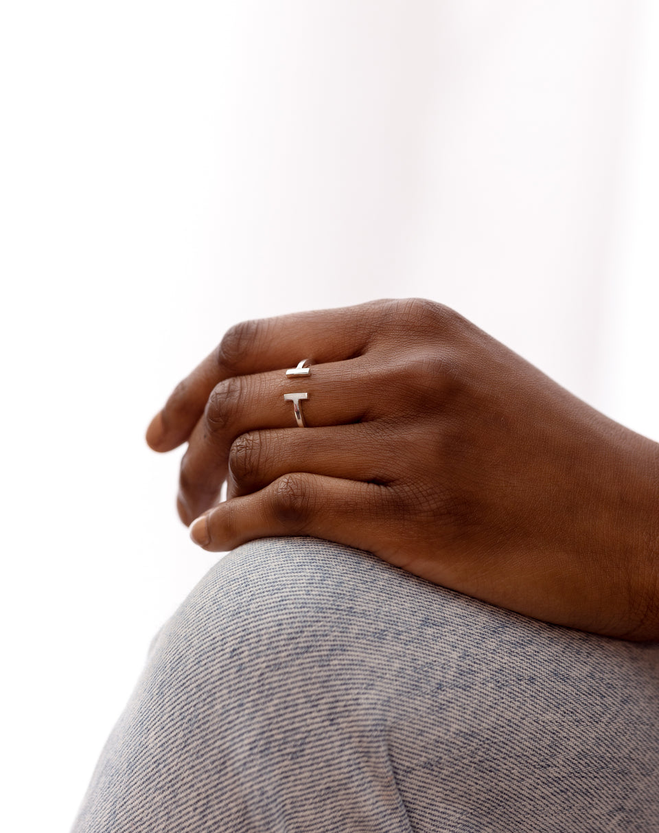 A model wears the Strict Bar Ring in silver, showcasing its open design with two parallel bar ends on her ring finger.