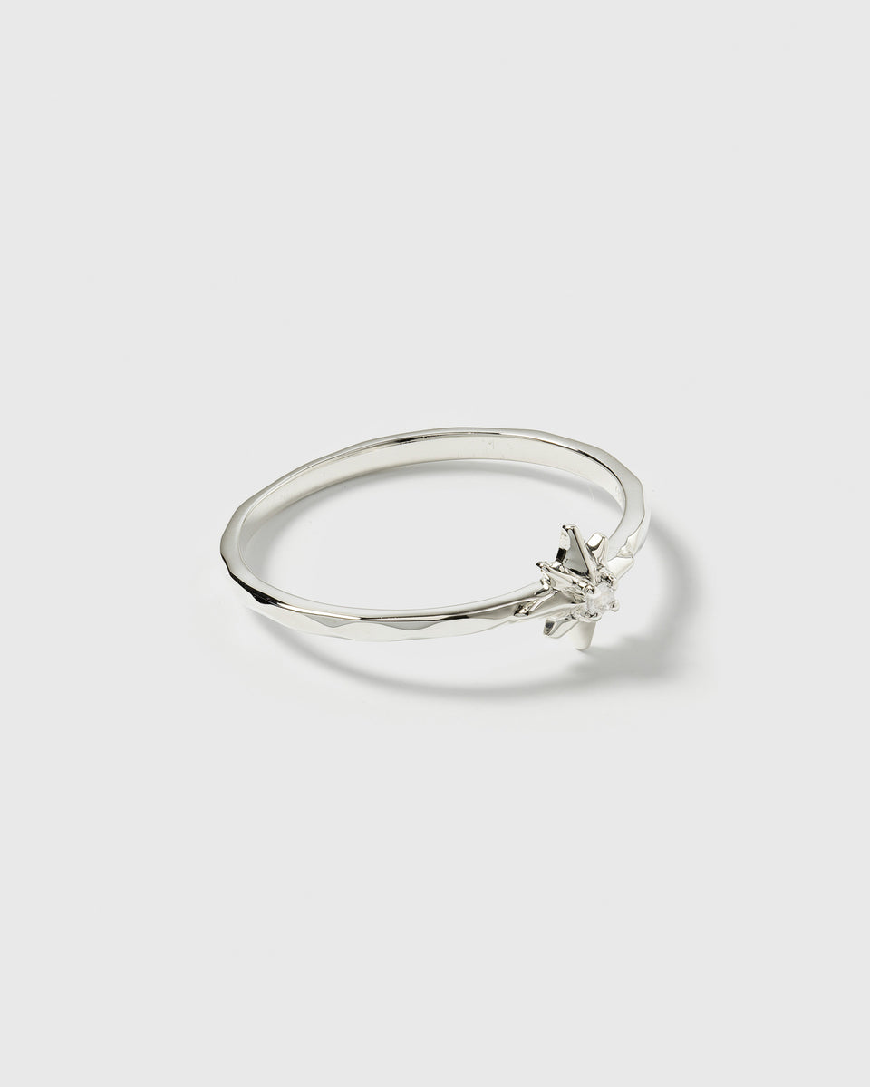 A product shot of the North Star Ring in silver, featuring a thin band decorated with a star and a faceted crystal.