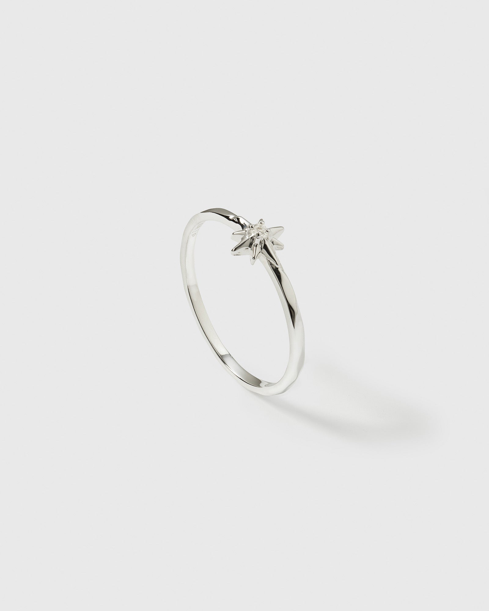 A product shot of the North Star Ring in silver, displaying its thin band and a star-shaped setting with a small crystal at its center.