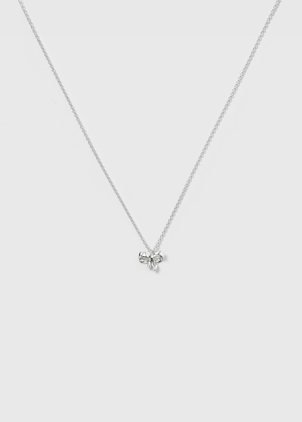 A product shot of the Rosie Mini Necklace in silver, featuring a delicate, sparkling chain and a small bow-shaped pendant.