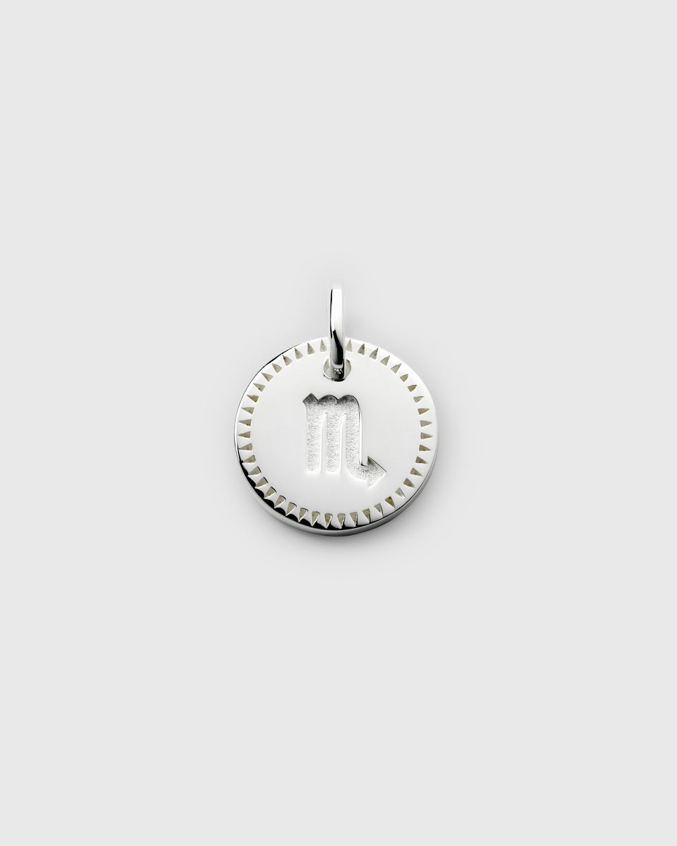 A product shot of the Beloved Zodie Pendant in silver, showing the round Scorpio charm with its engraved zodiac symbol and decorative border.