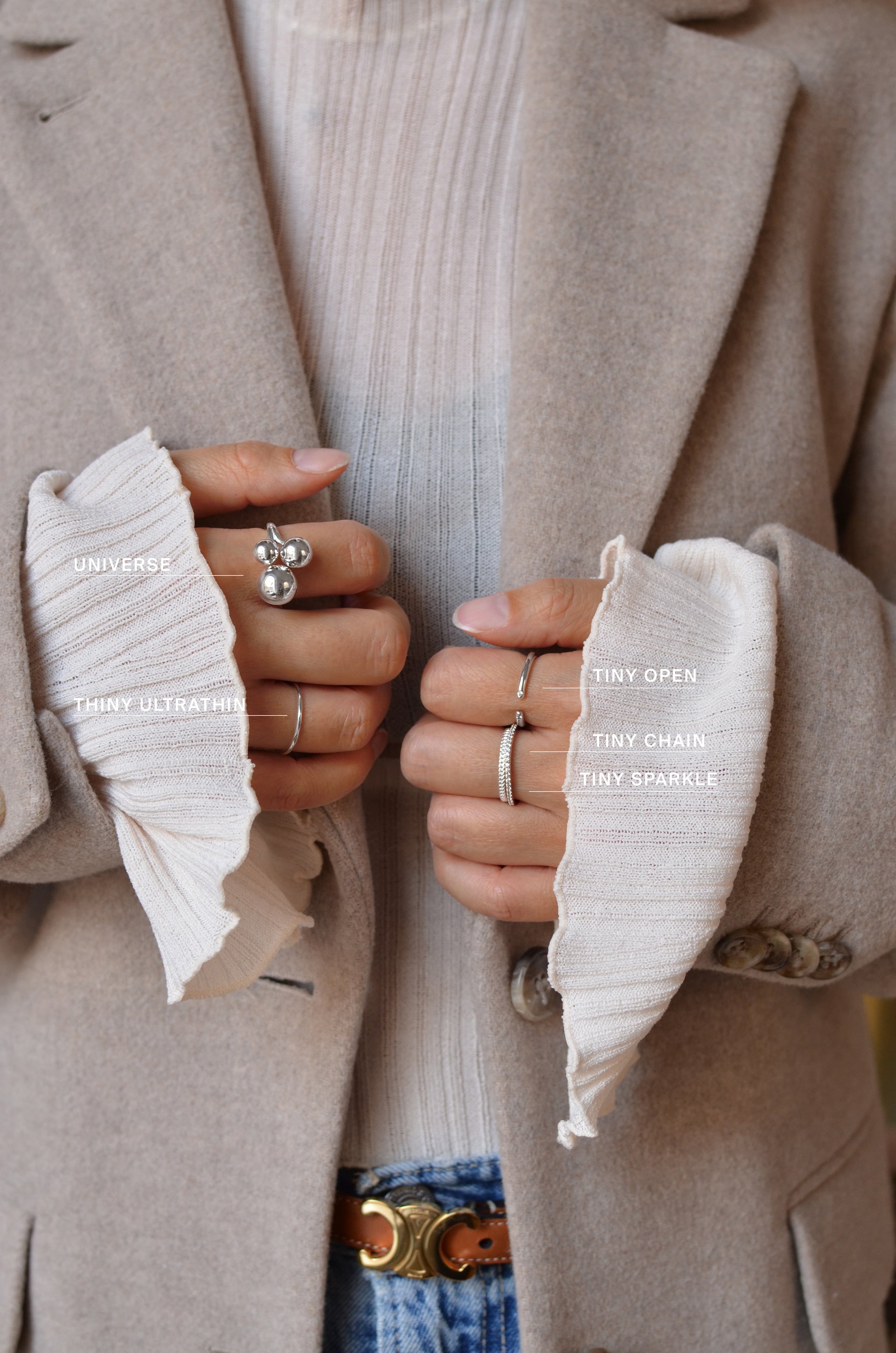 A hand with four different rings: A thin silver ring with a slightly structured surface, open gold ring with a cubic zirconia 